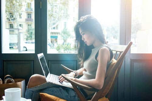 femme_frontalier_ordinateur femme asiatique assise sur une chaise devant son ordinateur portable