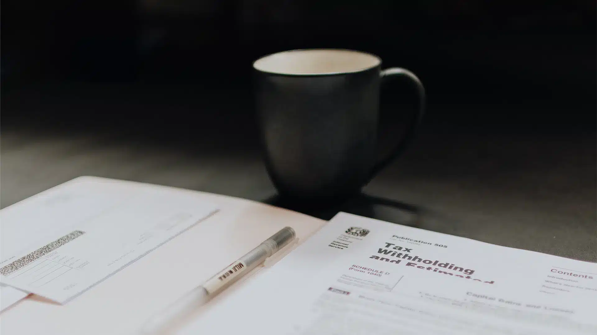 Documents fiscaux Tax Withholding avec stylo et tasse de café noir sur bureau